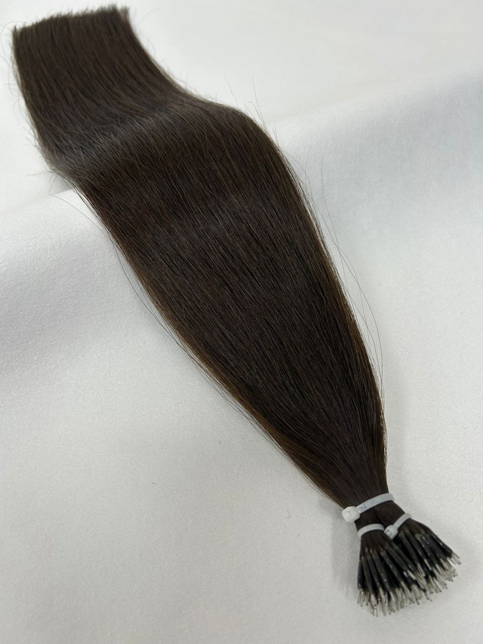 2 Darkest Brown nano tip hair extensions featuring ultra-fine tips for a lightweight, natural look. A deep, nearly black brunette shade for flawless blending.
