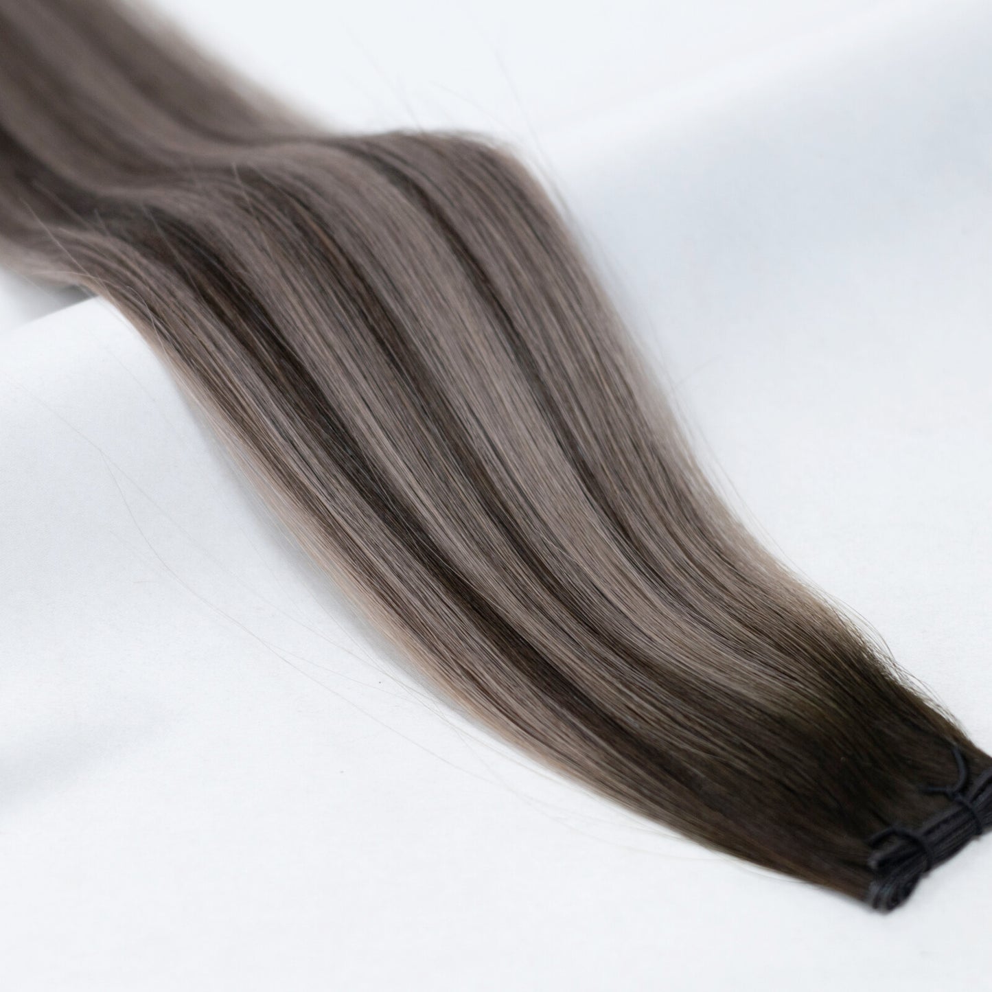 Subtle balayage hair extensions transitioning from dark brown to cool ash blonde. Available in Weft, Tape, Nano Tip, and Invisi Weft.