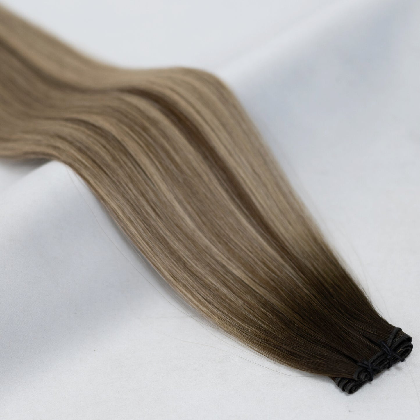 Multi-tonal balayage hair extensions blending dark brown, chestnut, and honey blonde. Available in Weft, Tape, Nano Tip, and Invisi Weft.