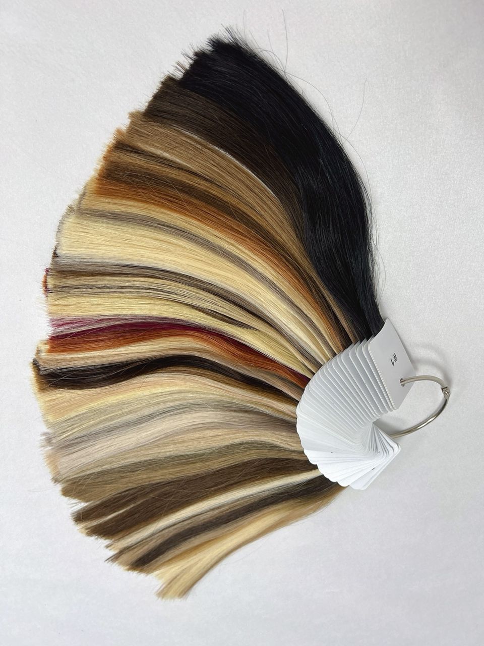 Professional hair extensions color ring displaying a range of rich brunettes, warm blondes, and multi-tonal balayage shades for accurate shade selection.