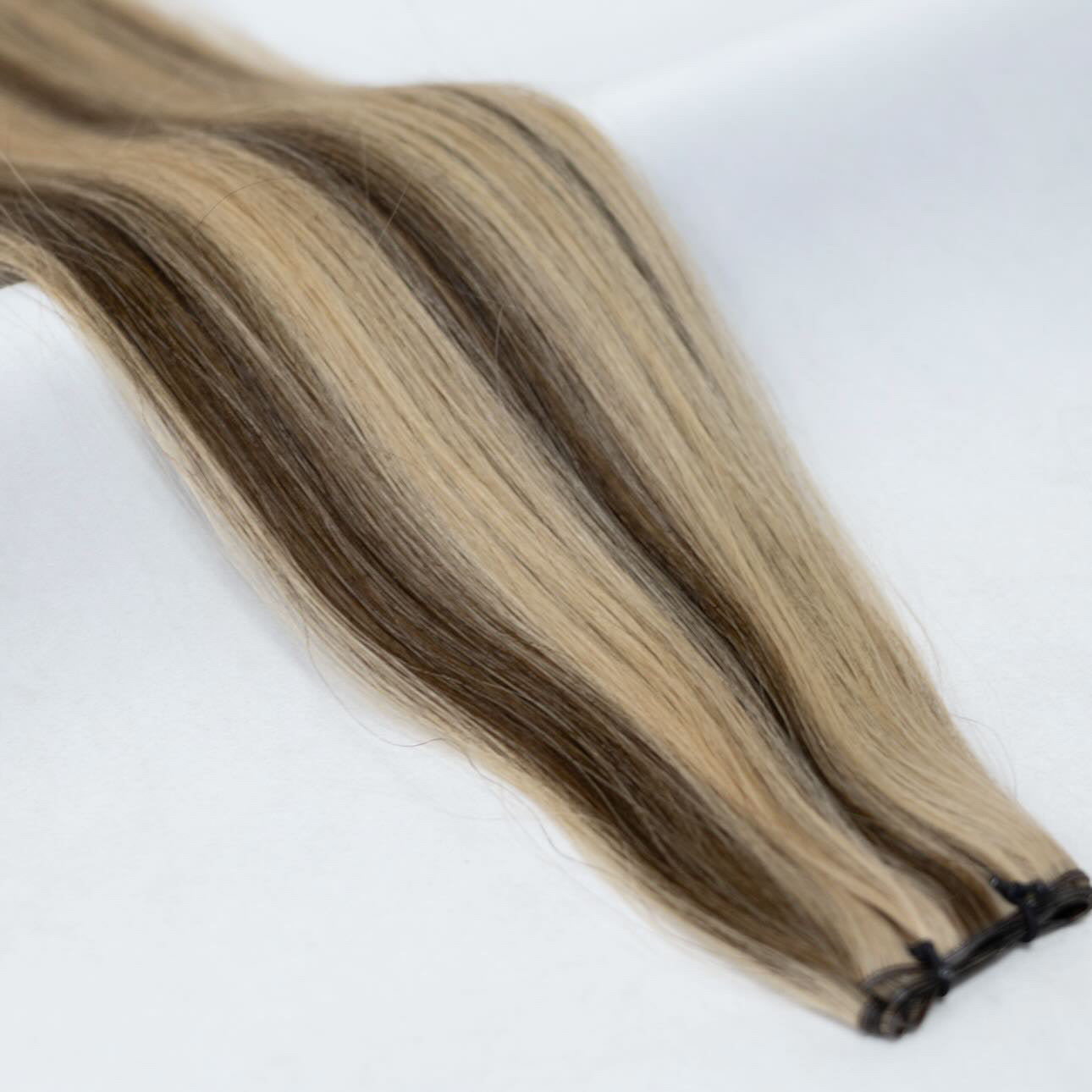 P4/27 hair extensions featuring a seamless blend of warm chestnut brown and golden honey blonde for a natural, radiant finish. Available in Weft, Tape, Nano Tip, and Invisi Weft.