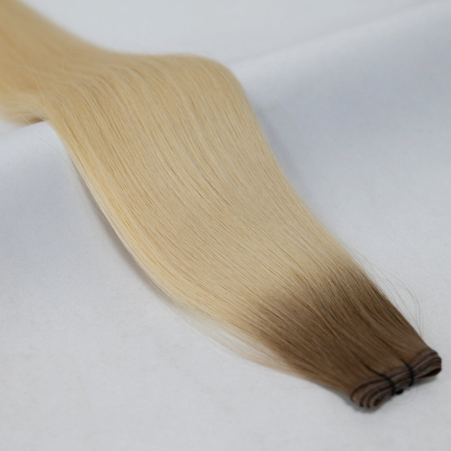 Ombre hair extensions transitioning from rich brown to bright platinum blonde. Available in Weft, Tape, Nano Tip, and Invisi Weft.