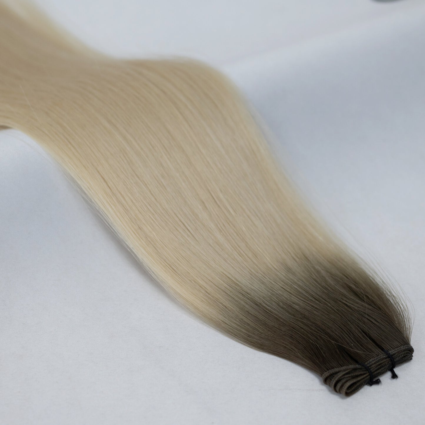 Ombre hair extensions transitioning from ash brown to platinum blonde for a seamless gradient. Available in Weft, Tape, Nano Tip, and Invisi Weft.